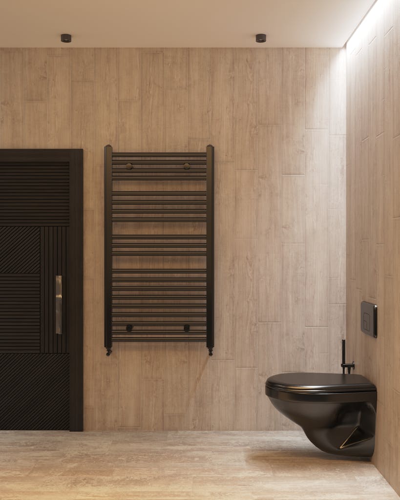 A modern minimalist bathroom interior featuring a sleek black toilet and heated towel rail.